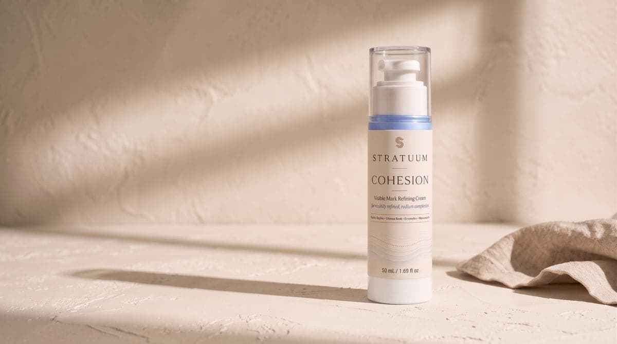 Stratuum Cohesion 50 mL airless cream bottle with ivory wrap label and blue formula.