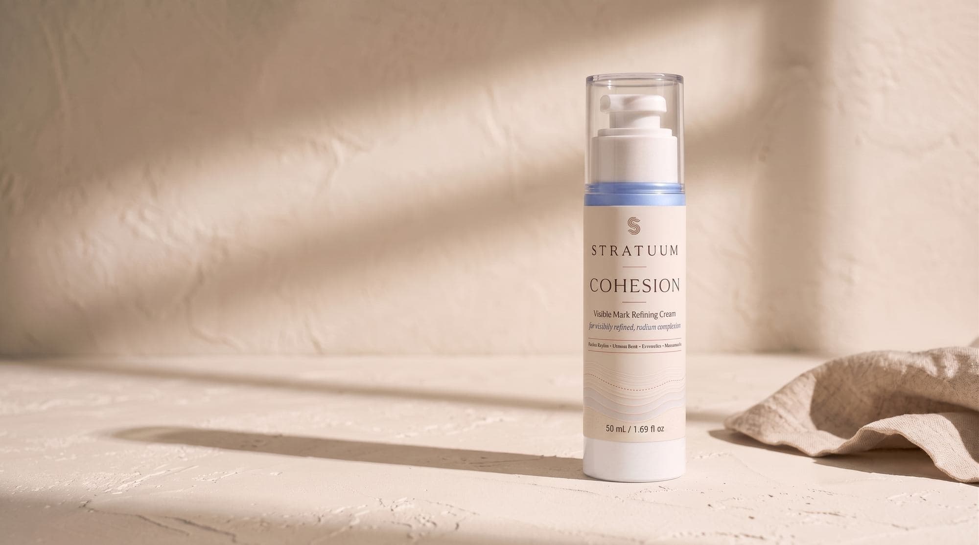 Stratuum Cohesion 50 mL airless cream bottle with ivory wrap label and blue formula.